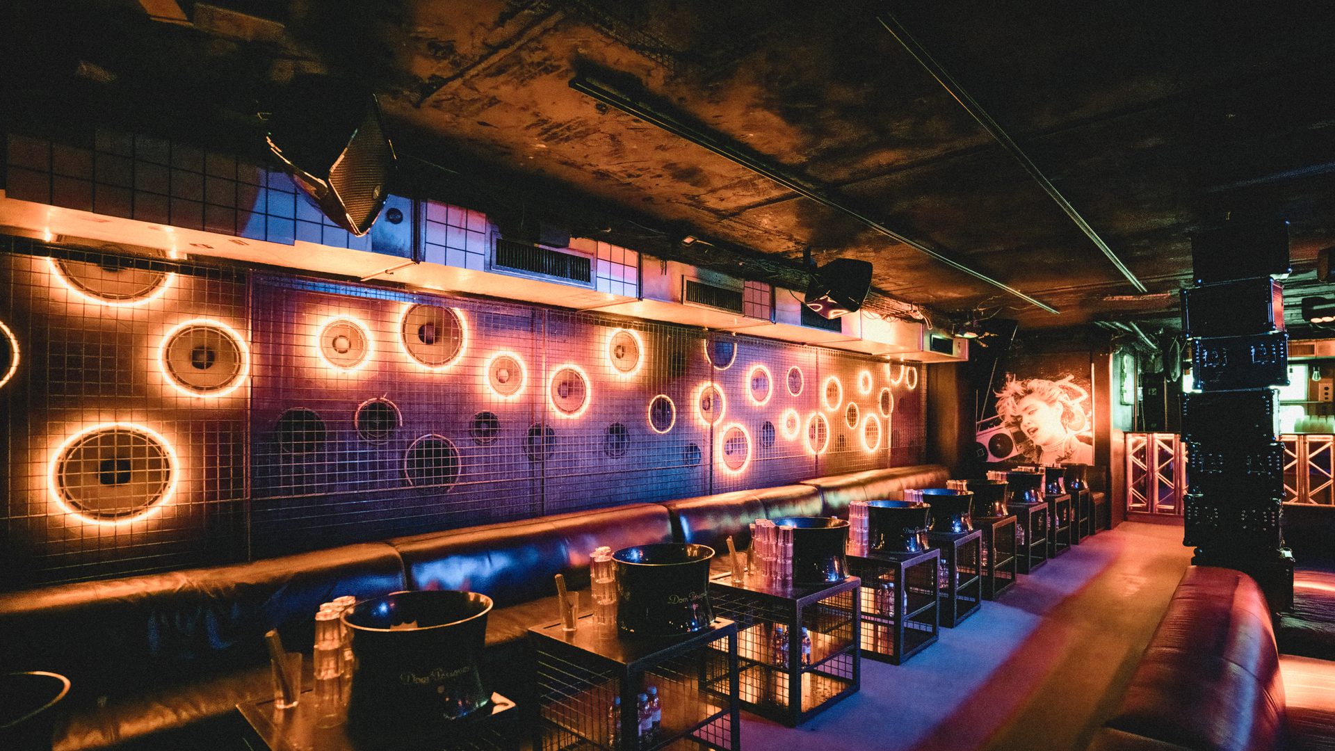 Club aux banquettes basses face à un mur de lumières circulaires