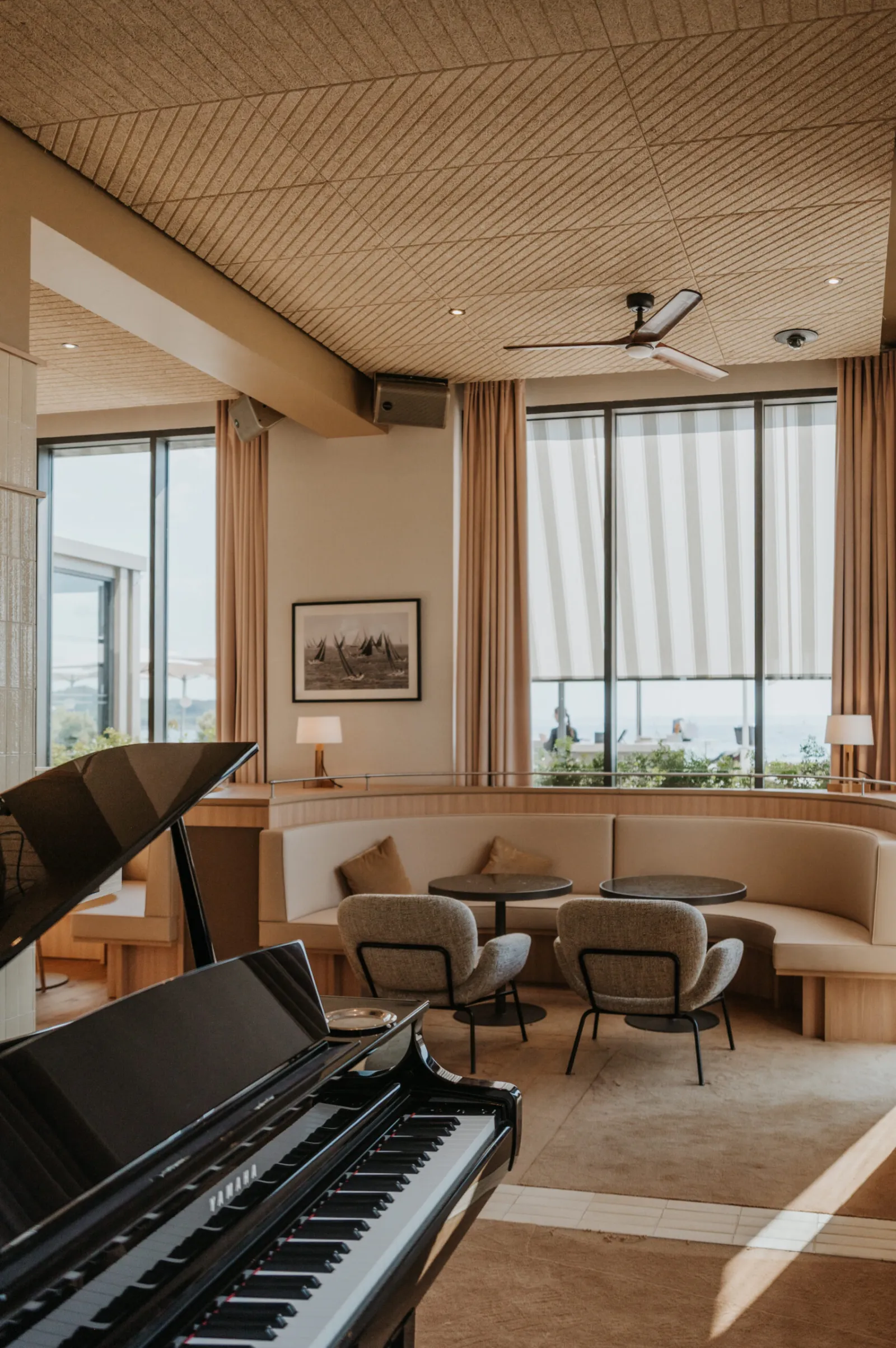 Salon d'hôtel lumineux : piano, fauteuils et grandes fenêtres