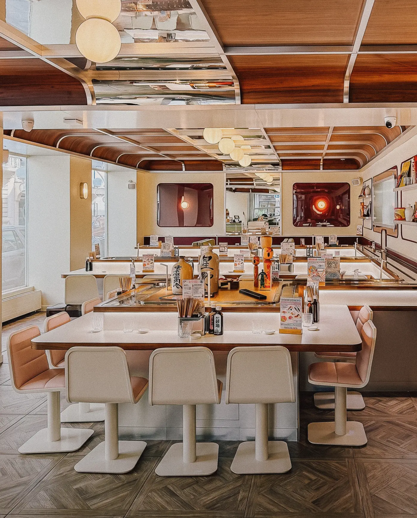 Salle de restaurant : comptoir central, tabourets clairs et plafond de bois cintré