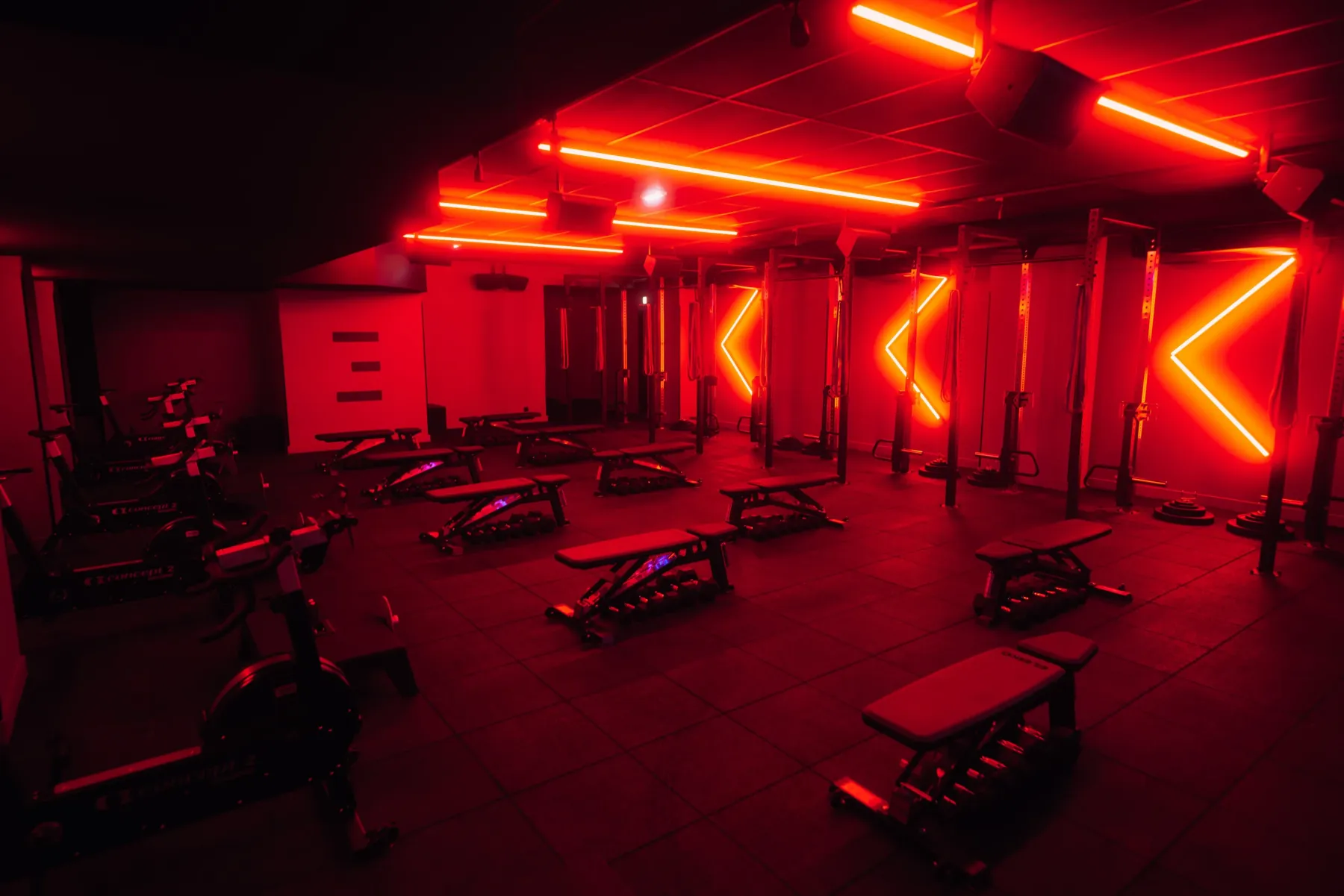 Episod Pigalle, Paris : salle d'entraînement sous des néons rouges, bancs, vélos et cages
